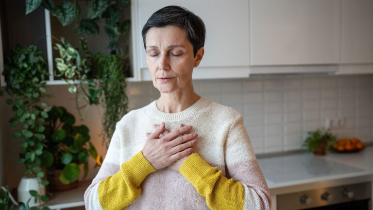 Eine Person steht mit geschlossenen Augen und den Händen auf der Brust in einem hellen Raum. Nutze Holotropes Atmen Sachsen für tiefgehende innere Prozesse.