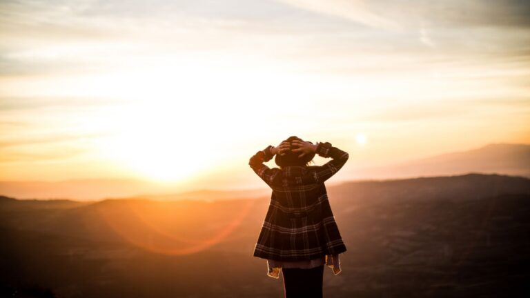 Eine Person steht in der weiten Natur und blickt entspannt in den Sonnenuntergang. Nutze bewährte Methoden für das Ziel Innere Unruhe loswerden Bautzen.