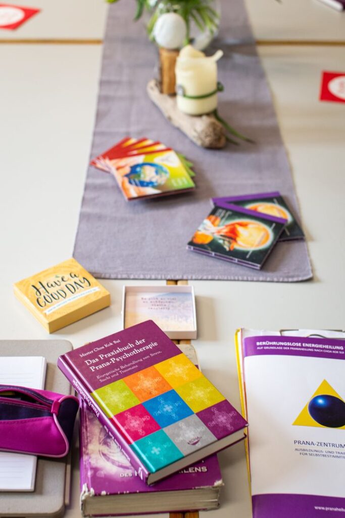 Auf einem Tisch liegen farbige Bücher sowie CDs und Schreibmaterialien für ein Seminar bereit um Wissen zur Pranaheilung in Bautzen zu vermitteln.